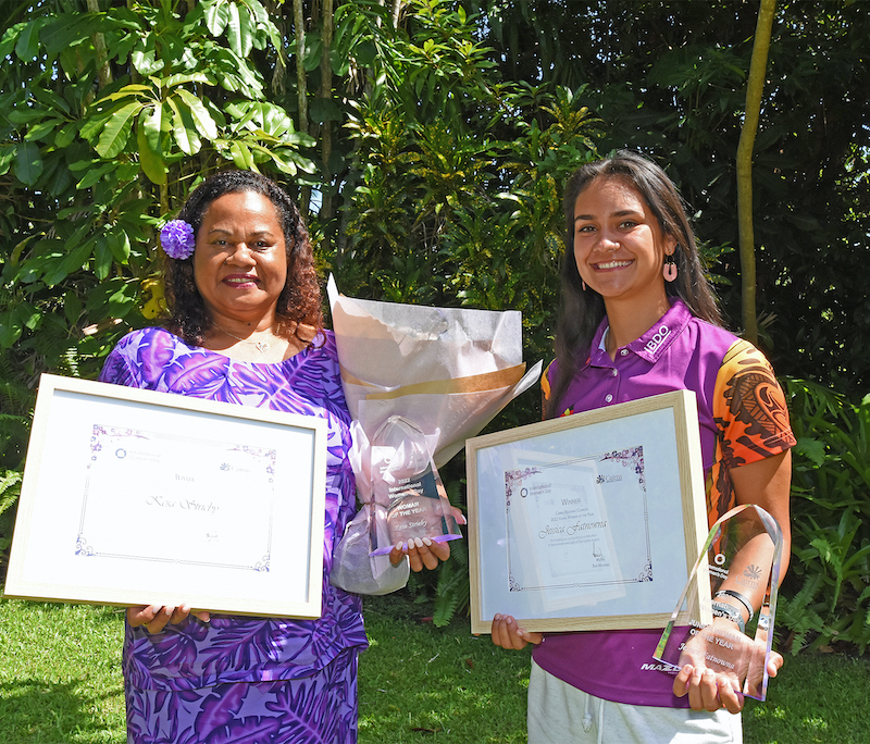 Jess standing with a lady while they hold certificates and a trophy